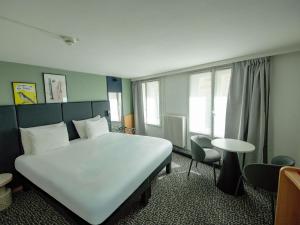 ein Schlafzimmer mit einem großen weißen Bett und einem Tisch in der Unterkunft ibis Paris Grands Boulevards Opéra 9e in Paris