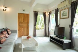 un salon avec un canapé et une télévision dans l'établissement Villa Reina Resort, à Nong Nam Daeng
