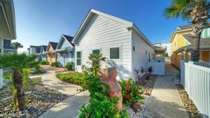 a white house with flowers and a sidewalk at Sleeps 18 2 Beach Homes w 2 Pools Playground Covered Patios Pirates Bay by AvantStay in Mustang Beach