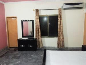 a bedroom with a bed and a mirror and a window at Orange Line Hotel in Dargai