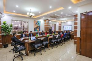 a group of people sitting at a long table in a room at FabHotel Frolic in Haridwār