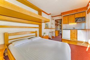 a bedroom with a white bed and a kitchen at Hauts de Vanoise 3 personnes Coeur Village in Val Thorens