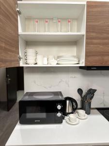a kitchen counter with a microwave and cups and saucers at Krystal Bakuriani resort hotel 202C in Bakuriani