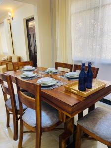 a wooden table with chairs and blue bottles on it at Boma Hill Residence Apartments by Monalisa in Morogoro