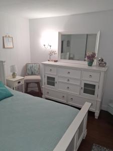a bedroom with a white dresser and a mirror at Waterfront Cottage in Marco Island