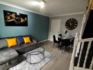 a living room with a couch and a table and a clock at 2 Bed House - Sleeps 6 - Parking - Wifi in Oldbury
