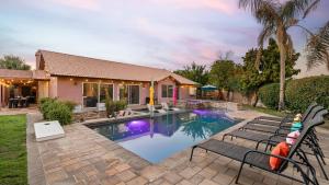 a home with a swimming pool with two chairs and a house at Luxury Oasis w Pool Hot Tub Fire Pit Games Big Yard Larrea by AvantStay in La Quinta