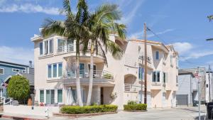 a white building with a palm tree in front of it at Shoreline Villa by AvantStay Steps to the Beach Bay Pier in Newport Beach
