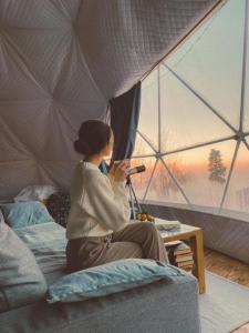 a woman sitting on a bed in a tent at Rum bubble in Disah