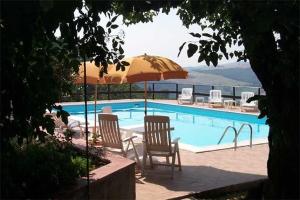 a swimming pool with two chairs and an umbrella at L'Oasi in Piano Delle Pieve