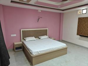 a bedroom with a bed in a pink wall at HOTEL KRISHNAM By TruStay in Satna