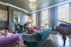 a living room with a couch and a piano at Luxury 4-Bed Regency Townhouse Overlooking Montpellier Gardens in Cheltenham