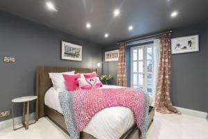 a bedroom with a bed with pink pillows at Luxury 4-Bed Regency Townhouse Overlooking Montpellier Gardens in Cheltenham