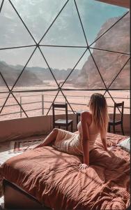 a woman sitting on a bed in front of a window at Rum prens in Wadi Rum