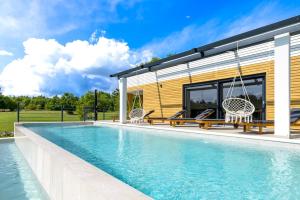 a swimming pool with two chairs and a house at Villa Japlenica by Istrialux in Žagrići