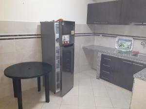 a small kitchen with a refrigerator and a table at Les géraniums in Agadir nʼ Aït Sa