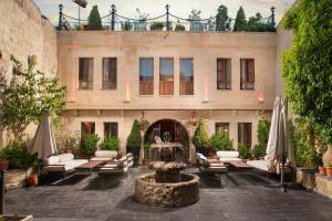 于尔居普Aja Cappadocia Cave Hotel的建筑前带喷泉的庭院