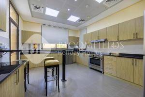 una cocina con armarios de madera, mesa y sillas en Bloomfields 3Br Villa Mina AlFajer with private pool, en Rūl Ḑadnā