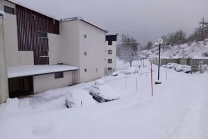 Una calle cubierta de nieve con un edificio y coches cubiertos de nieve. en Apartment With Balcony In Gérardmer, en Gérardmer