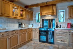 a kitchen with wooden cabinets and a black oven at Finest Retreats - Town Farm Cottage in Exbourne