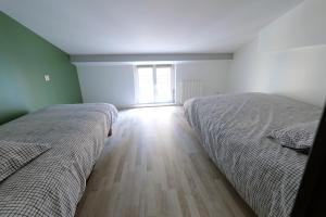 two beds in a bedroom with a window at Duplex cosy centre historique 2 ch 3 lits linge serviettes inclus 5 pers tout à pied in Le Puy en Velay