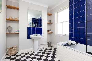 a bathroom with blue tiles and a sink and a tub at Characterful City Maisonette for 4 in Chichester