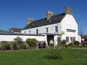 a group of people sitting outside of a white building at Bannockburn Inn in Helmsdale