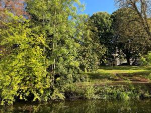 un cuerpo de agua con árboles y una casa en Logement indépendant dans une péniche, en Metz