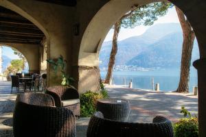 eine Terrasse mit Stühlen und Blick auf das Wasser in der Unterkunft Gritti Palace Morcote - Salvia - Loft by the lake with view of Morcote's church in Morcote
