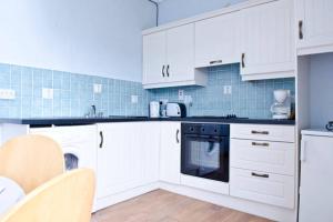 a kitchen with white cabinets and a black oven at Cooraclare apartment in Cuar an Chláir