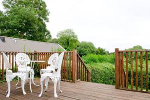 two white chairs and a table on a wooden deck at Cooraclare apartment in Cuar an Chláir