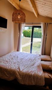 una camera da letto con un letto e una grande finestra di Chalet romantique & bucolique a Montignac-Charente