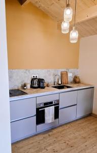 una cucina con mobili bianchi e un lavandino di Chalet romantique & bucolique a Montignac-Charente