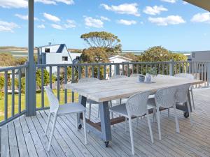 a wooden table and chairs on a deck at Beilby Inlet Views in Inverloch