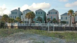 a row of houses on the beach with palm trees at 110 Grand Pavilion by AvantStay Direct Access To Grand Pavilion Boardwalk in Isle of Palms