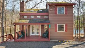 a red house with two chairs on the porch at Pirate-Themed Lakefront Home w Kayaks Game Room Views Hidden Treasure Hunt in East Stroudsburg