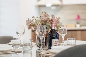 a bottle of wine sitting on a table with glasses at Luxury Designer Apartment - Romanescu Park in Craiova