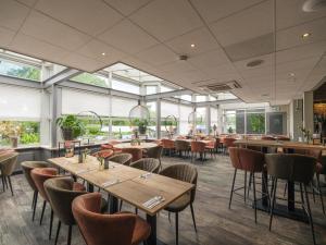a restaurant with tables and chairs and windows at Vakantiepark Ackersate in Voorthuizen