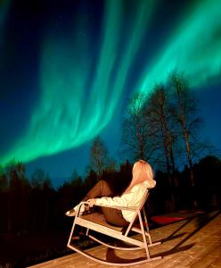 a person sitting in a chair under the northern lights at Kajo Sky Lodge in Rovaniemi