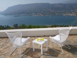 two chairs and a table on a patio overlooking the water at Panoramic Seaview Holiday House in Souda