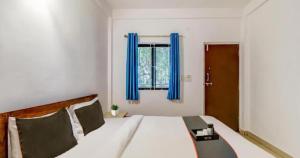 um quarto com uma cama com cortinas azuis e uma janela em Aqua Wave by YogiTree Hotels em North goa