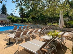 un gruppo di sedie e un ombrellone accanto a una piscina di Camping les Pialades - Gite a La Mouline