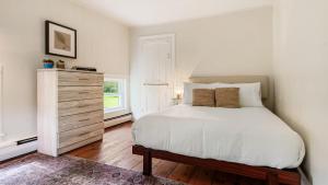 a bedroom with a white bed and a dresser at Pondfront Gem Minutes from Hudson’s Best Shops Cafes The Stillwater House in Hudson