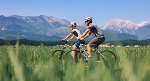 a man and a woman riding bikes through a field at Altitude50 apartment Domžale in Domžale
