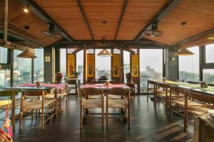 a restaurant with tables and chairs and windows at Kecho Legacy Hotel Hanoi & Spa in Hanoi