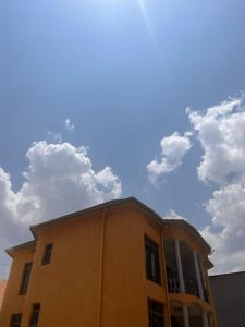 キガリにあるSAMNDAMZ Villa Apartmentの空に雲が浮かぶ黄色い建物