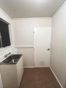 ウェリントンにあるSunny private room with private bathroomの白いキッチン(シンク、ドア付)