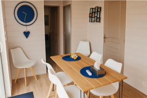 a dining room with a wooden table and white chairs at Chalet Charmant à Louer pour 4-6 Personnes dans le Morvan Rouvray 21 avec SPA in Rouvray