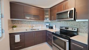 a kitchen with brown cabinets and a stove and microwave at Aquaville Dorado Moderna Villa 5 in Dorado