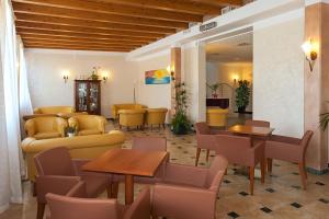 poczekalnia ze stołami i żółtymi krzesłami w obiekcie Regent's Hotel w mieście Lido di Jesolo
